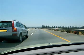 מבט מתוך רכב על כביש מהיר עם מספר נתיבים באותו כיוון נסיעה. בין הנתיבים מסומן קו הפרדה מקווקו לבן, ורכב נוסף נוסע בנתיב השמאלי.