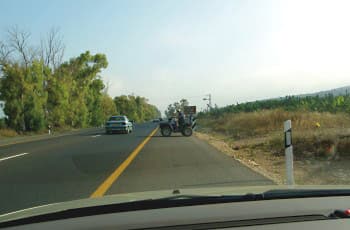 טרקטורון נוסע על השול הימני של כביש בין-עירוני. פס הפרדה צהוב רציף מפריד בין השול לנתיב הנסיעה.