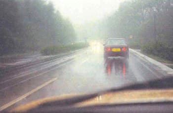 מבט מתוך רכב על כביש רטוב, כאשר רכב אחר נוסע מלפנים. הראות לקויה מאוד עקב ערפל כבד המכסה את כל הסביבה.