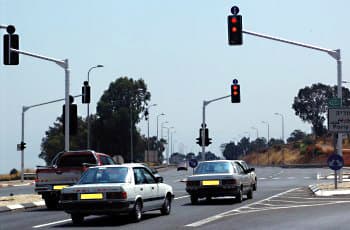 בתמונה נראה צומת עם כלי רכב העומדים לפני רמזור. ברמזורים הפונים אל כלי הרכב דולקים בו-זמנית האור האדום והאור הצהוב.