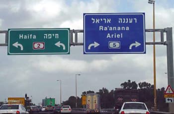 בתמונה נראים שני תמרורי הכוונה גדולים מעל הכביש. התמרור השמאלי הוא מלבני ירוק, המורה על פנייה שמאלה לחיפה ומציין את כביש מספר 2. התמרור הימני הוא מלבני כחול, המורה על פנייה ימינה לרעננה ואריאל ומציין את כביש מספר 5.