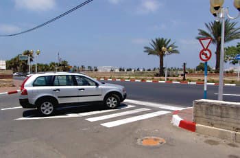 בצד הדרך, לפני צומת, מוצבים שני תמרורים: למעלה תמרור משולש הפוך של "תן זכות קדימה", ומתחתיו תמרור עגול האוסר פנייה שמאלה. על הכביש מסומן מעבר חצייה.