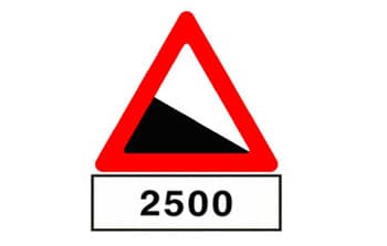 בתמונה תמרור אזהרה משולש עם מסגרת אדומה, שבתוכו סמל של ירידה תלולה. מתחת לתמרור המשולש יש שלט מלבני לבן עם המספר 2500.