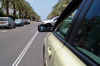 התמונה מציגה כביש דו-סטרי, שבמרכזו מסומן קו הפרדה רצוף כפול. בצד ימין של התמונה נראה חלק מרכב, כולל מראת הצד שלו.