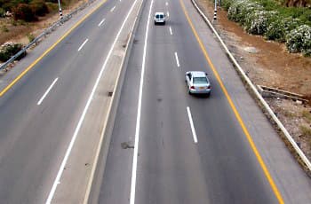 התמונה מציגה דרך מהירה עם מספר נתיבים, המופרדים באמצעות גדר הפרדה. בצד ימין של הכביש נראה שול דרך סלול, המופרד מהנתיב הימני באמצעות קו הפרדה רצוף בצבע צהוב.