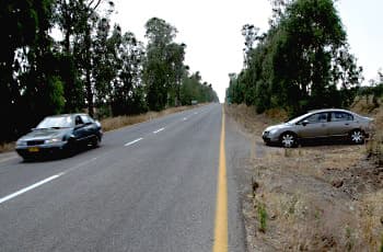 בתמונה נראה כביש סלול עם רכב הנוסע בו. לצד הכביש, על דרך עפר, עומד רכב נוסף הפונה לכיוון הכביש במטרה להשתלב בתנועה.