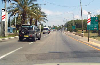 בכביש נראים שני תמרורים מלבניים אנכיים, אחד מכל צד. בכל תמרור יש חץ שחור הפונה שמאלה בחלקו העליון, ומתחתיו פס אלכסוני אדום אחד. בצד ימין יש גם תמרור הכוונה ירוק המורה על פנייה שמאלה למעלות, ישר לנהריה ועכו, וימינה לכברי.