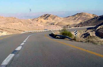 כביש דו-סטרי עם קו הפרדה רצוף צהוב, המתעקל בחדות שמאלה באזור הררי. בצד ימין של העיקול מוצב תמרור 801 (חץ הכוונה שחור-לבן), ושדה הראייה קדימה מוגבל.